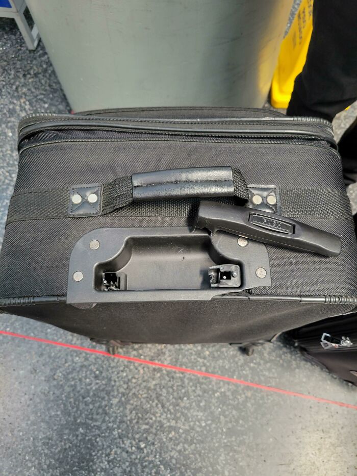 Broken handle on a black suitcase highlights an epic airline baggage fail.