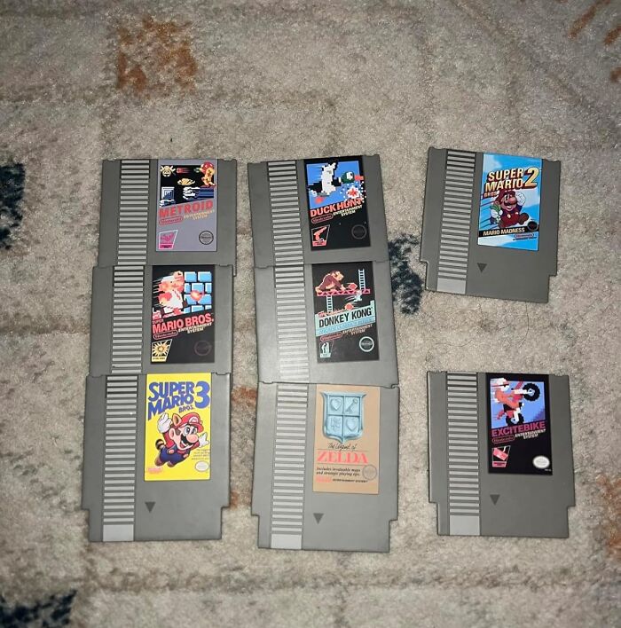 Vintage 80s NES game cartridges, including Super Mario and Zelda, spread out on a carpet.