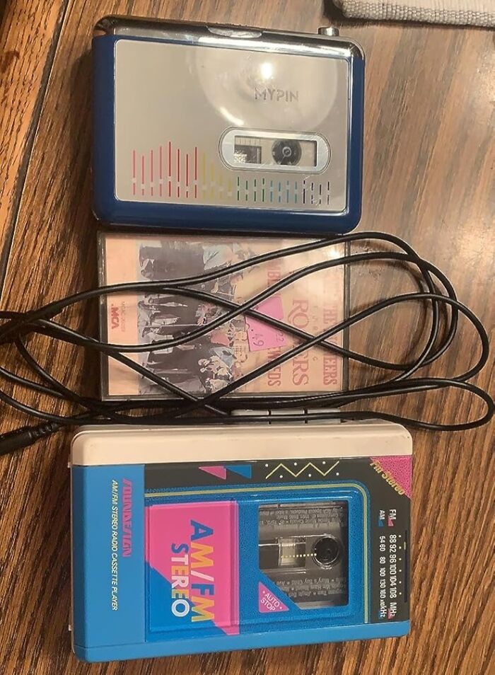 80s kids' treasures: vintage cassette players and tapes on a wooden surface.