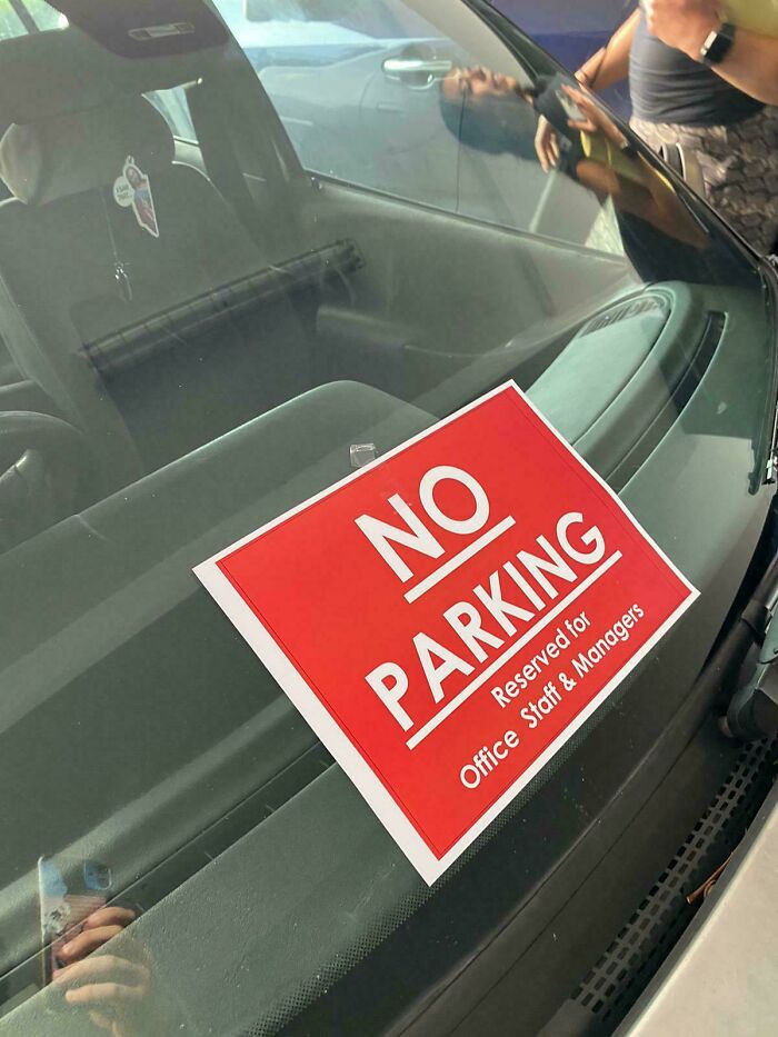 Red 'No Parking' sign on car windshield, marked for office staff, illustrating a worst day at work scenario.
