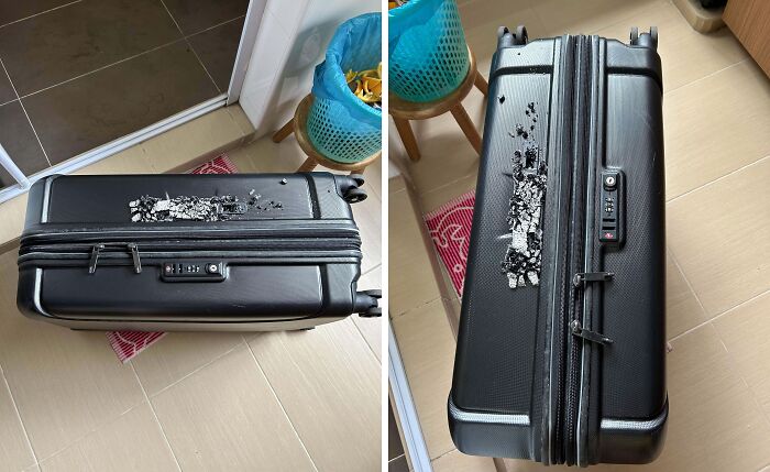 Damaged airline baggage with a shattered hard shell on the floor, showing severe breakage.