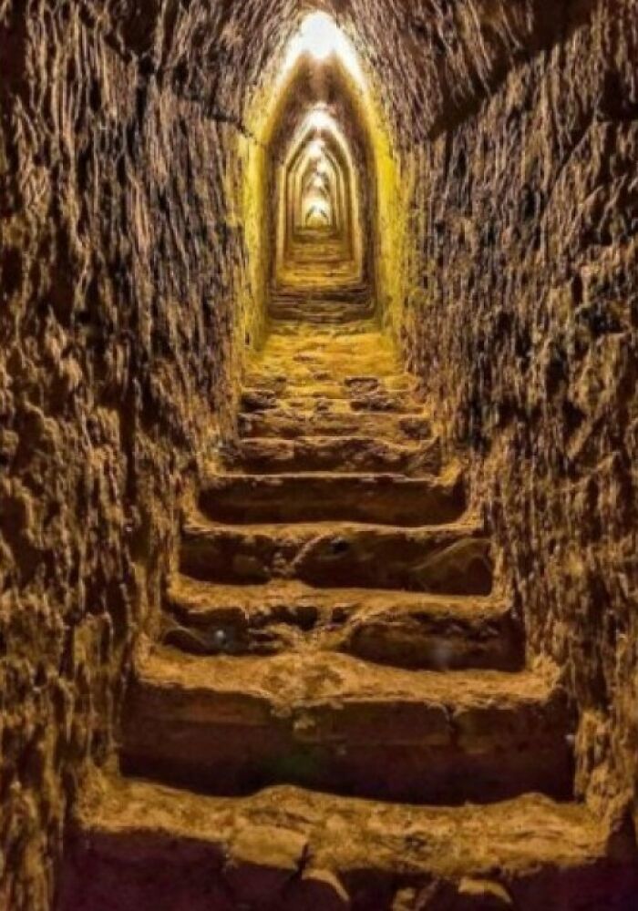 Ancient explorers' stone stairway in a dimly lit tunnel, showcasing historical preservation.