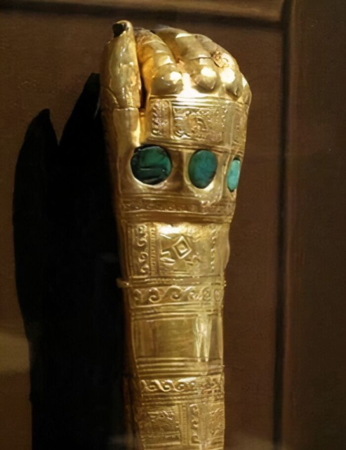 Ancient explorers artifact: a golden armored hand with turquoise inlays, showcasing intricate craftsmanship from the past.
