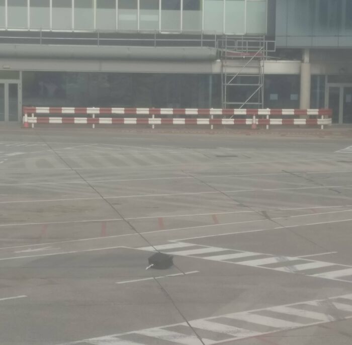 Abandoned suitcase on airport tarmac, showcasing airline baggage fail amidst desolate surroundings.
