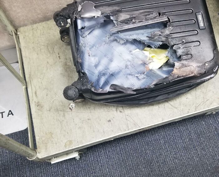 A damaged suitcase with a large hole and burnt edges, illustrating an epic airline baggage fail.