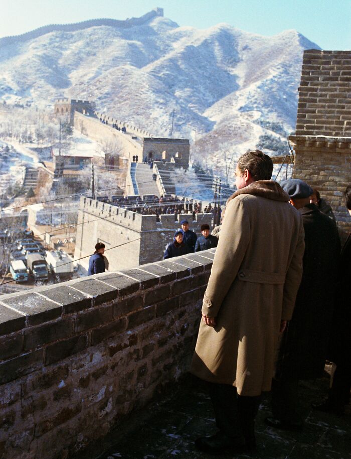 A person in a coat observing the Great Wall of China, a historical turning point in scenic winter surroundings.