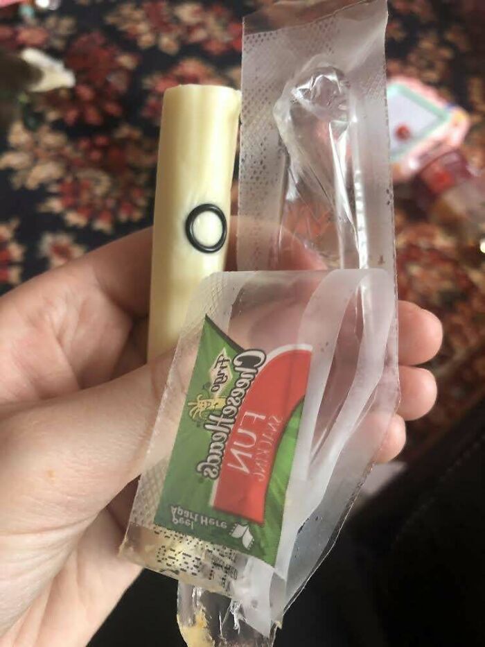 Person holding string cheese with a worm inside, illustrating a disgusting food find.