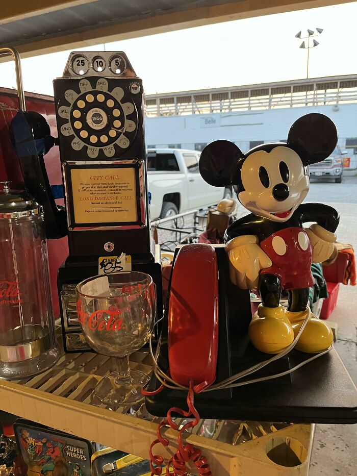 Vintage rotary phone and figurine displayed on a table with collectible items around.