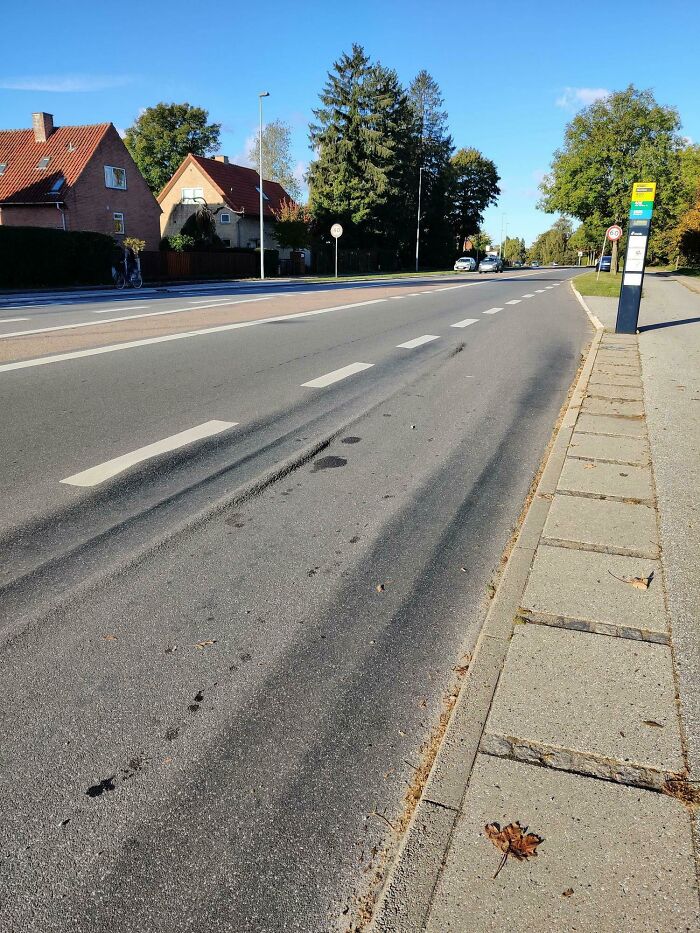 A road showing wear from time with grooves and marks near a suburban street.