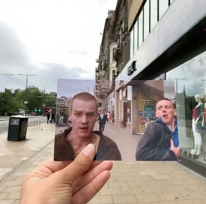 Person holds photo aligning movie scene with a real Scottish street, capturing the humor of location matching.