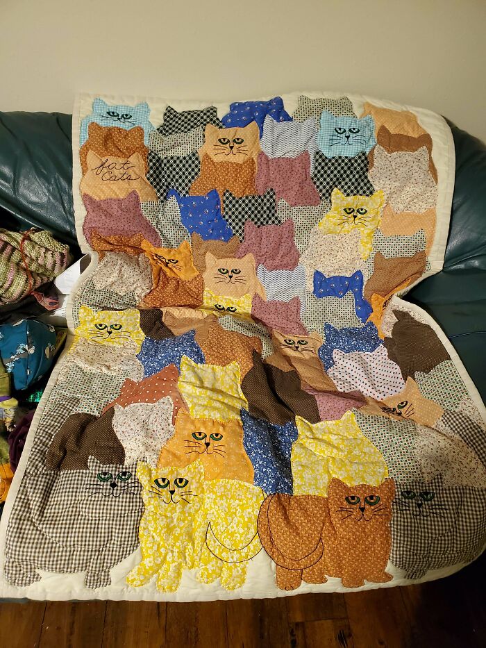 Vintage patchwork quilt with colorful cat designs on a couch.