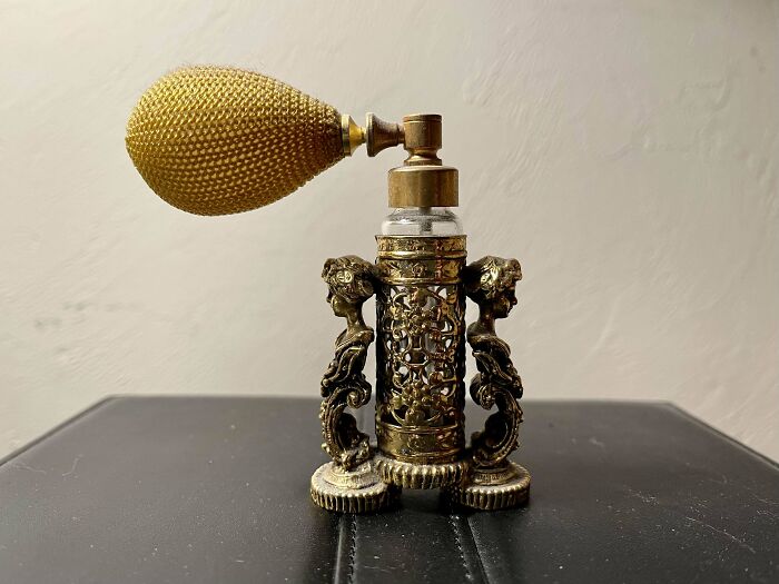 Intricately designed vintage perfume bottle with ornate gold details and a bulb atomizer, showcasing its collectible value.