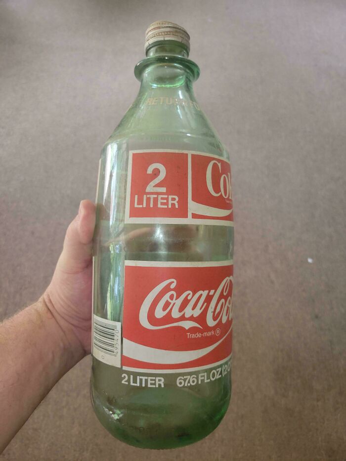 Vintage Coca-Cola 2-liter bottle being held, showcasing classic design and collectible value.