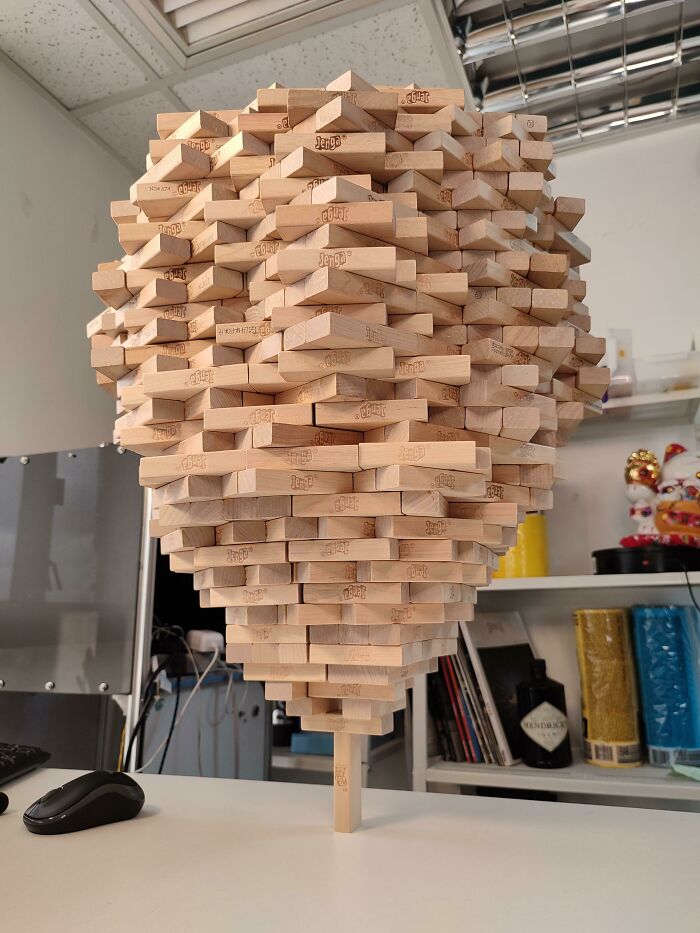 Bloques de Jenga formando una estructura surreal en equilibrio sobre una mesa en una oficina.