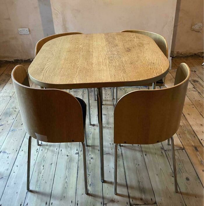 Vintage wooden dining table with chairs on rustic wooden flooring.