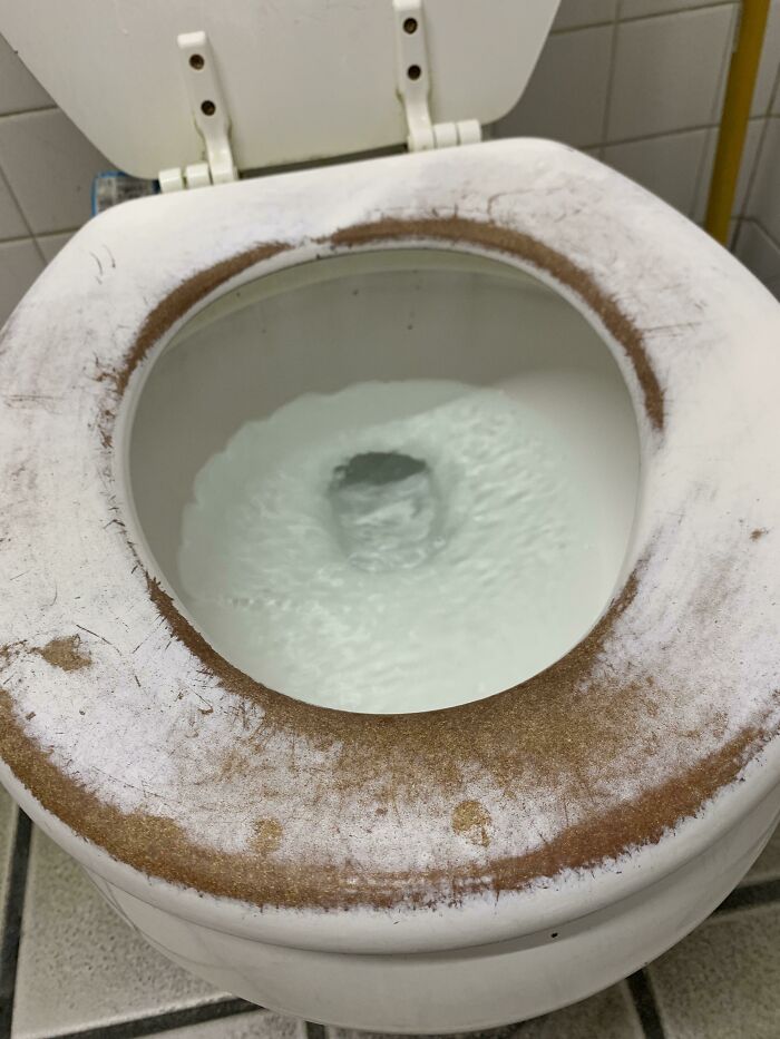 Worn-down toilet seat showing signs of aging and time, with visible discoloration and wear.