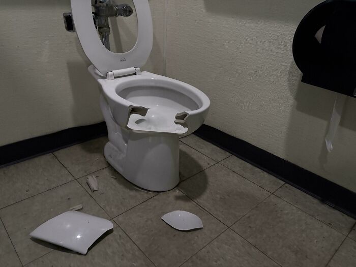 Broken office restroom toilet with scattered pieces, illustrating a worst day at work scenario.