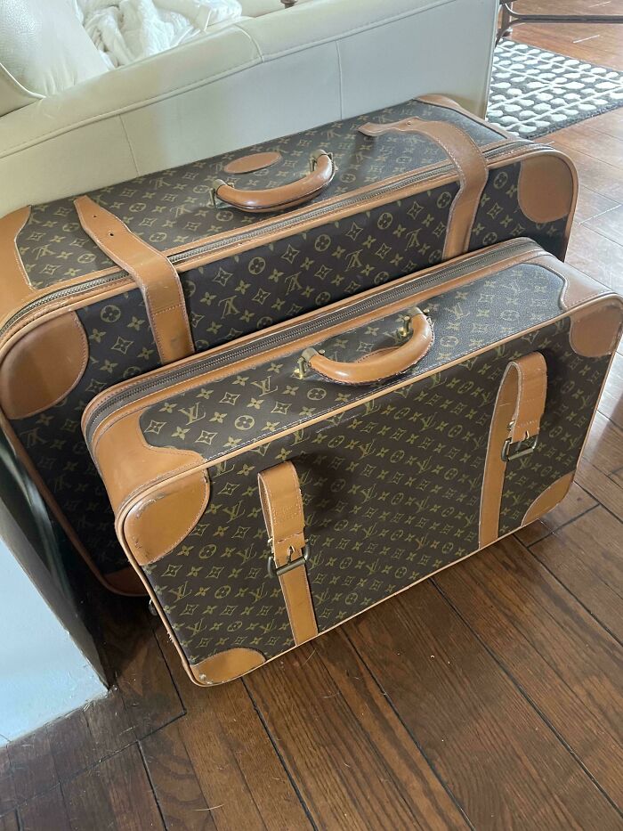 Vintage Louis Vuitton suitcases with a monogram pattern, resting on a wooden floor.
