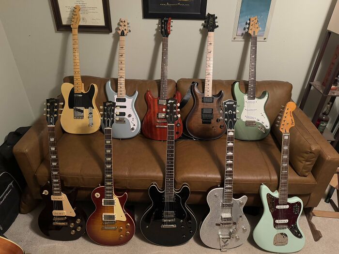 Vintage guitars displayed on a brown couch, showcasing collectible musical instruments.