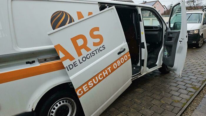 Damaged logistics van with a broken door on a cobblestone road, showing a worker's worst day at work.