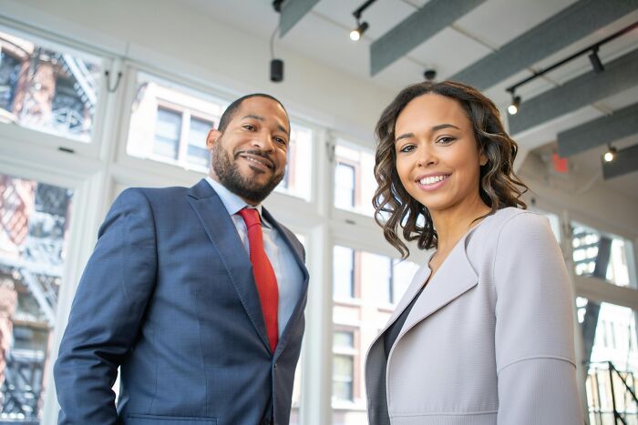 Two professionals in office attire smiling, symbolizing overused office expressions.