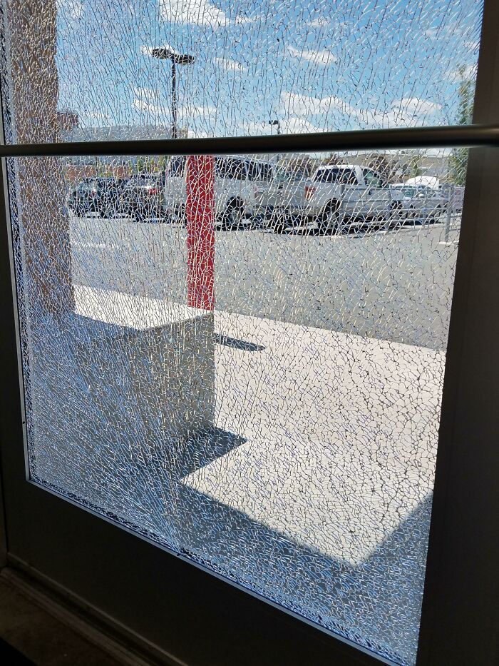 Shattered glass door in a workplace casts intricate shadows, symbolizing a bad day at work.