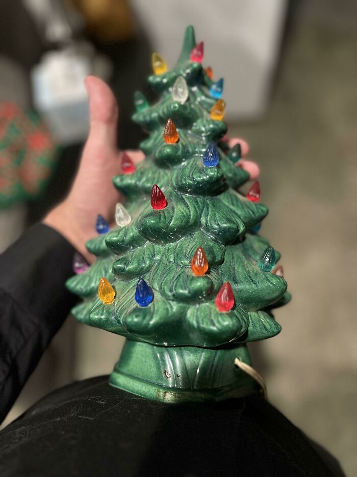 Vintage ceramic Christmas tree with colorful lights held in a hand.