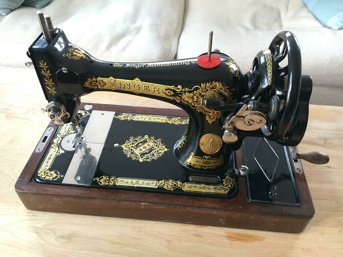 Vintage Singer sewing machine with ornate gold details on a wooden base.