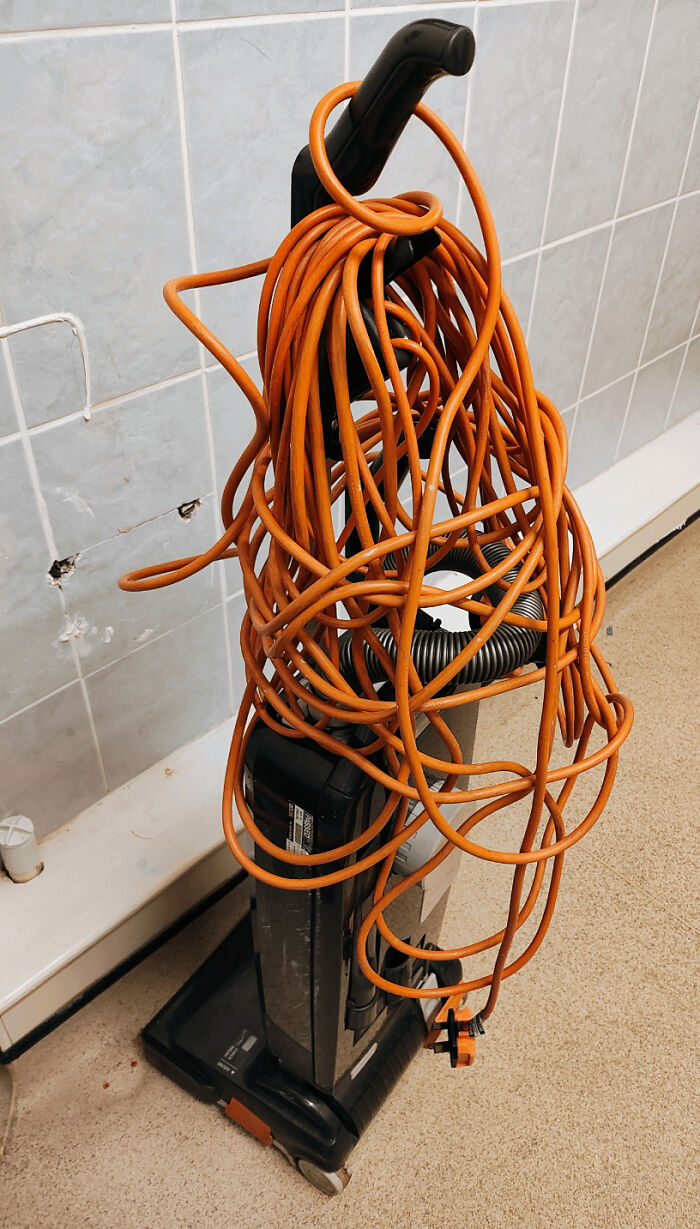 Vacuum cleaner with a tangled orange cord, exemplifying the frustration of working with worst colleagues.