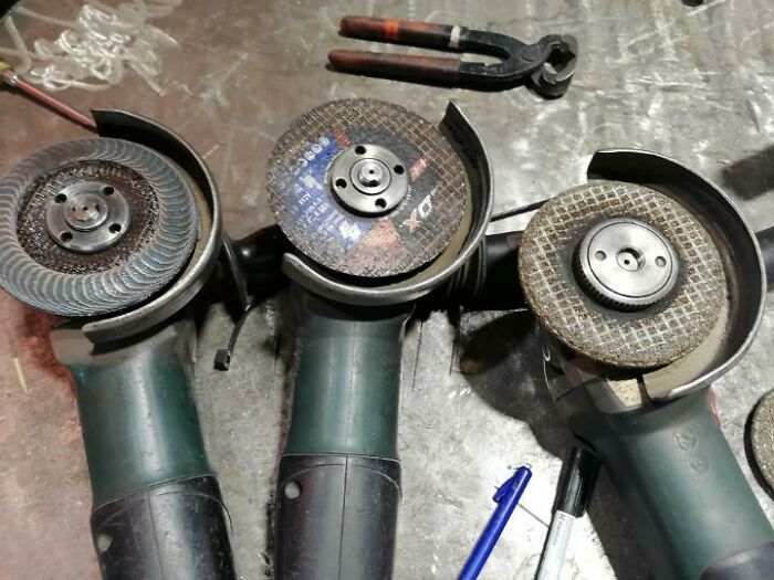 Three unused angle grinders on a workbench, illustrating workplace challenges with colleagues.