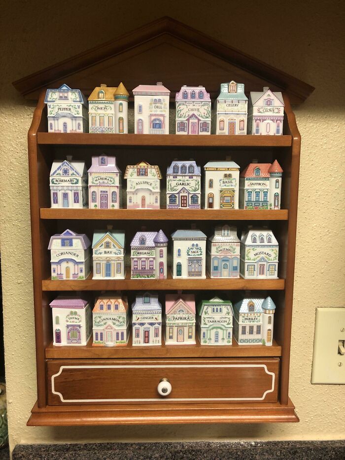 Miniature vintage spice houses displayed on wooden shelf.