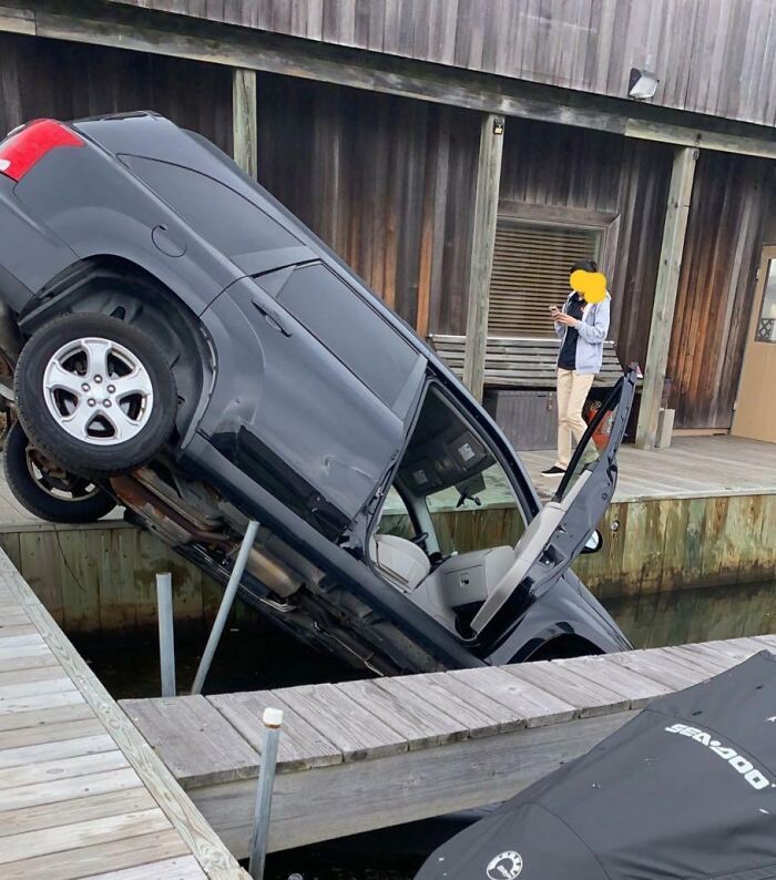 Car nose-down in marina accident, worker documenting a worst day at work.
