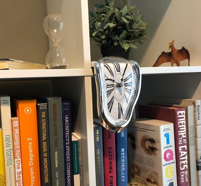 Melting clock on a bookshelf, surrounded by books and decor, creating a show-stopping visual centerpiece.