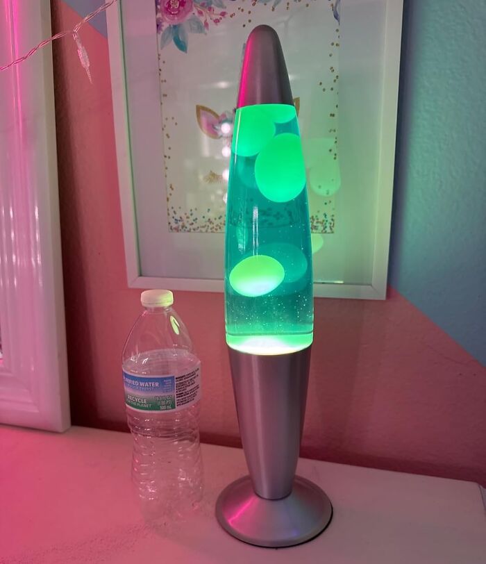 Colorful lava lamp glowing on a desk beside a plastic bottle, set against a decorative wall, a show-stopping find.
