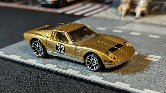 Vintage model car, gold with number 32, on a miniature road, collectible item.