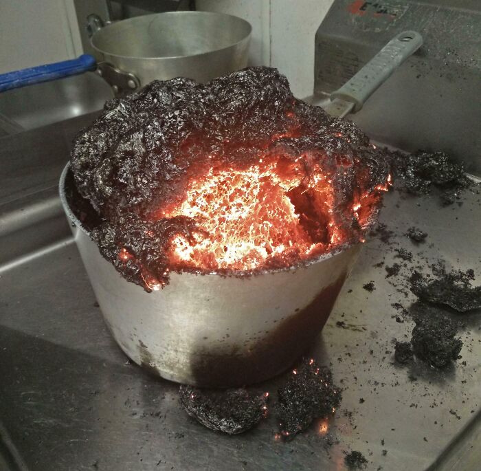 Burnt food overflowing a pot in a kitchen, representing a worst day at work scenario.