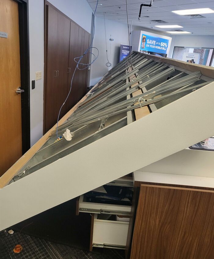 Office mishap with collapsed ceiling, exposed wires, and open cabinets, showcasing a workplace disaster.