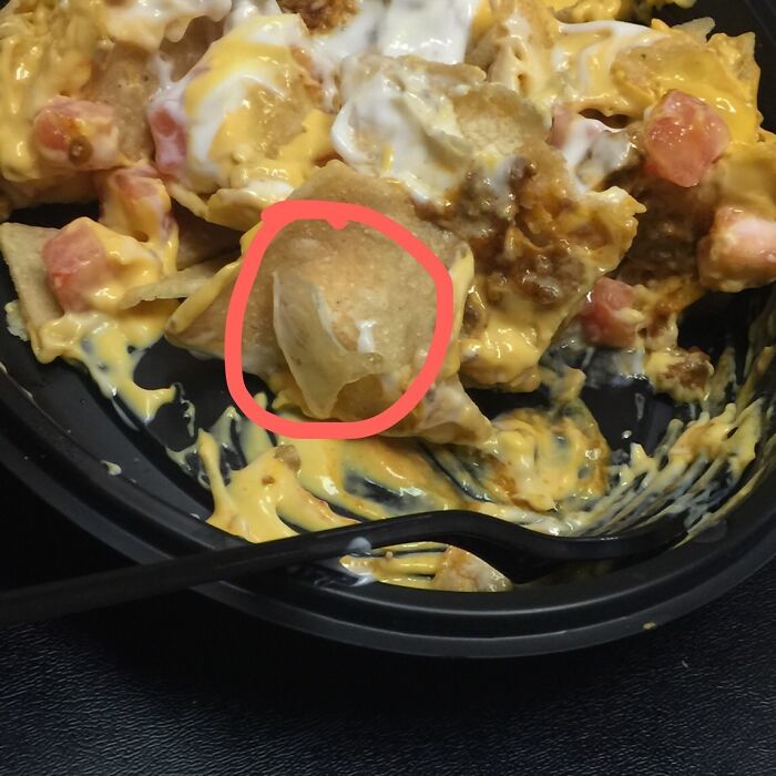 Nachos with unexpected item in red circle, showcasing a food experience turned disgusting.
