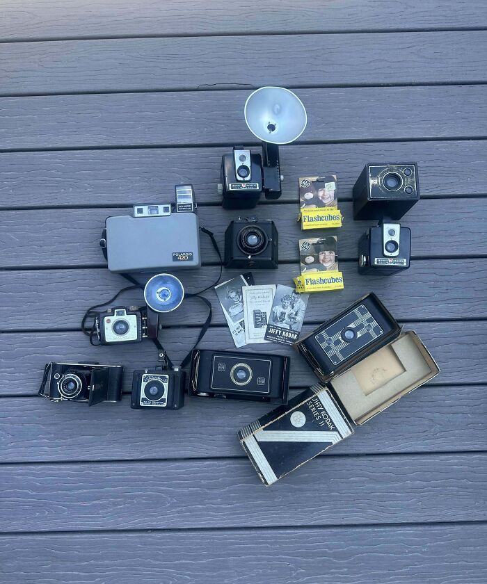 Vintage cameras and flashcubes arranged on a wooden surface.
