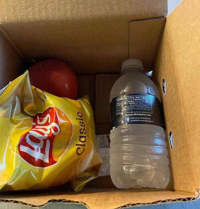 A cardboard box with Lay's chips, apple, and water bottle, symbolizing a worst day at work snack.