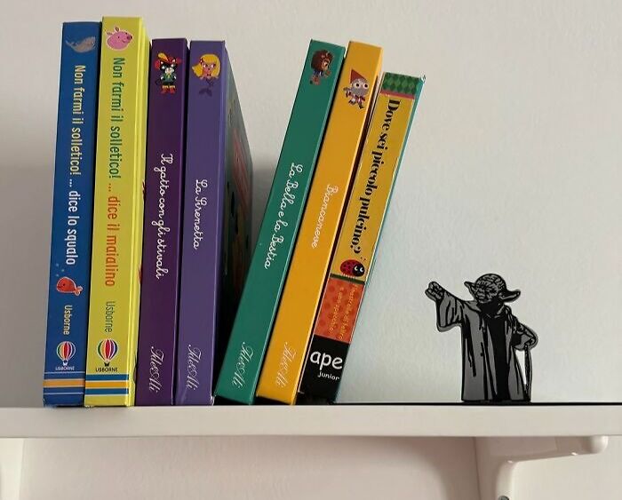 Books leaned against a figurine on a shelf, illustrating humor and creativity, embodying office Olympics spirit.