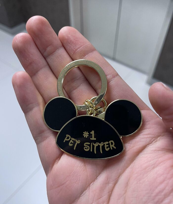 Hand holding a keychain with "#1 Pet Sitter" in gold lettering.