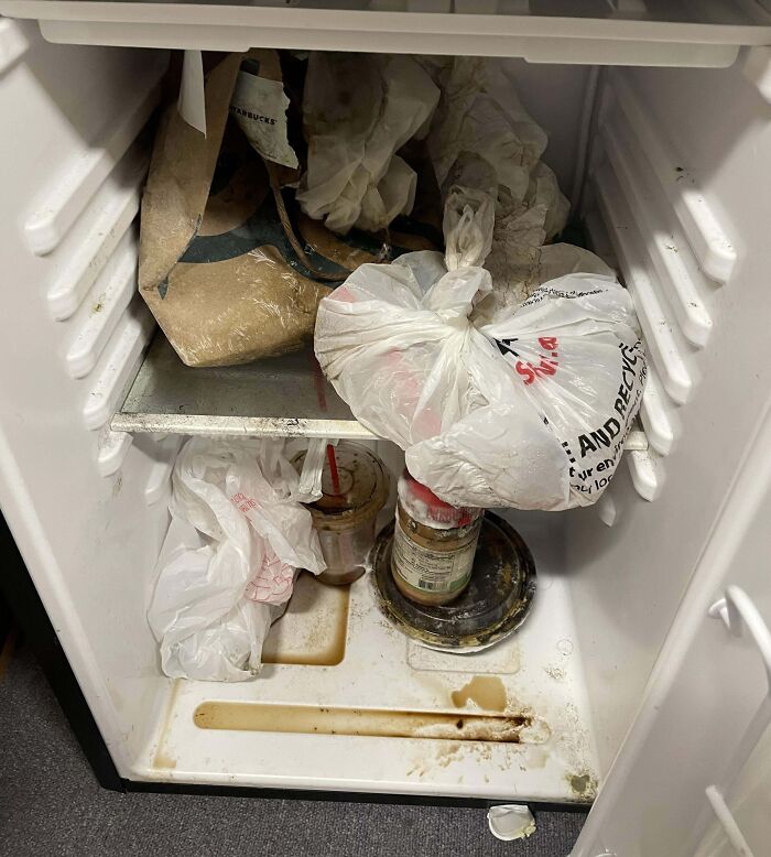 Messy office fridge with spilled drinks and spoiled food, showcasing worst colleagues in workplace hygiene.
