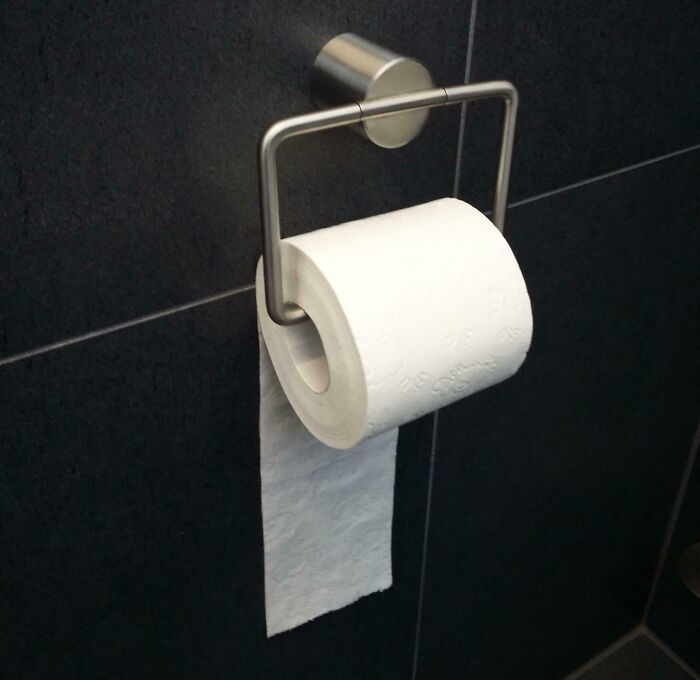 Toilet paper roll installed backwards in a restroom, highlighting workplace colleague issues.