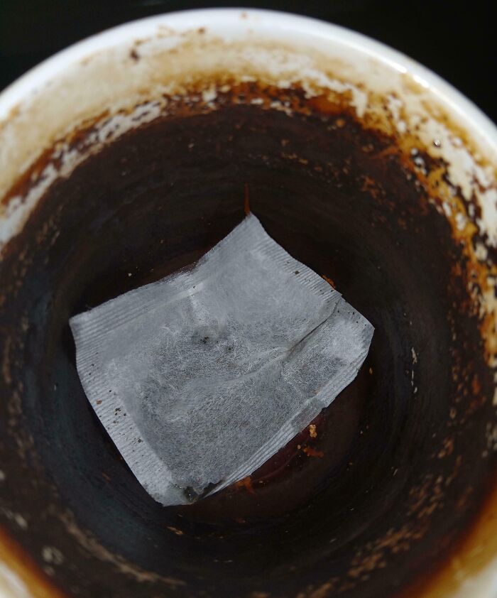 Dirty mug with a tea bag left inside, highlighting a frustrating colleague experience.