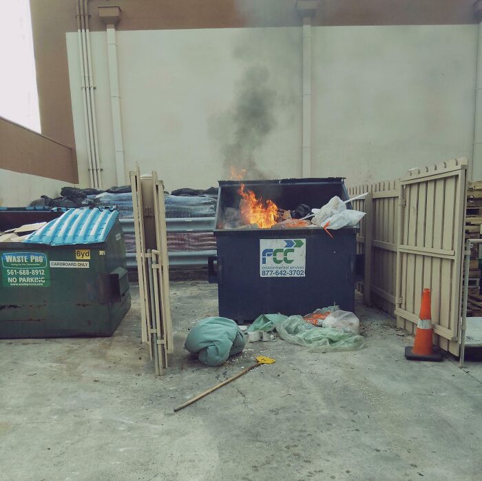 Dumpster fire in a workplace area, illustrating worst colleagues scenario with flames inside the trash bin.
