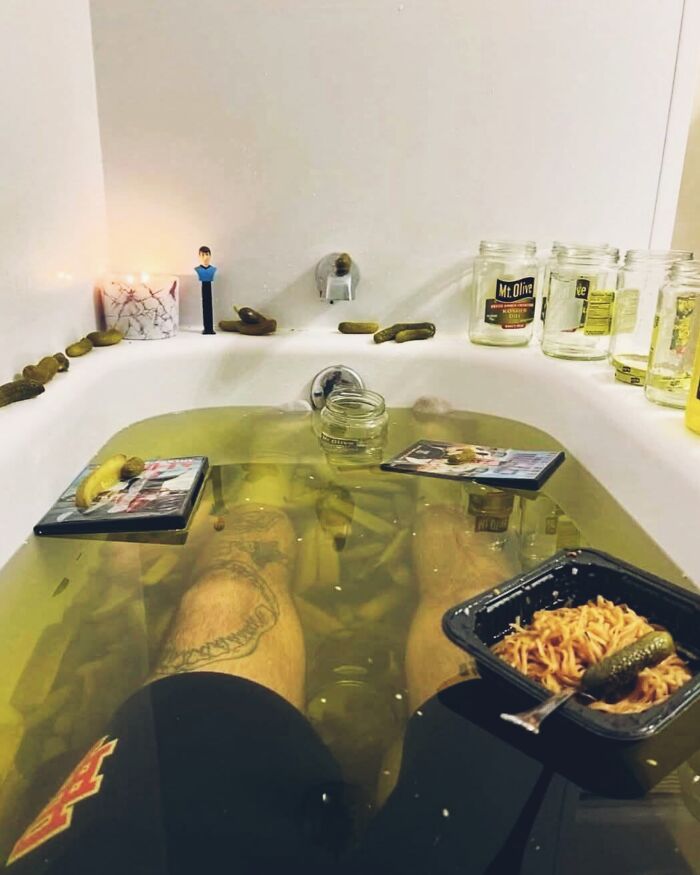 Persona sumergida en bañera con encurtidos y fideos instantáneos, mostrando opiniones y posturas escandalosas en internet.