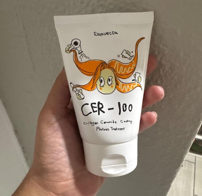 CER-100 protein treatment tube for curls with quirky illustration in hand.