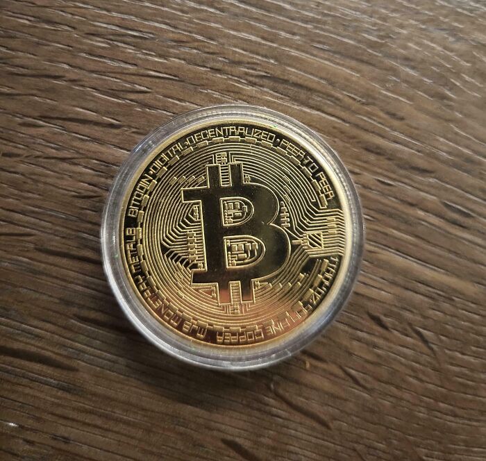 Bitcoin in protective case on wood surface, symbolizing a tough workday.