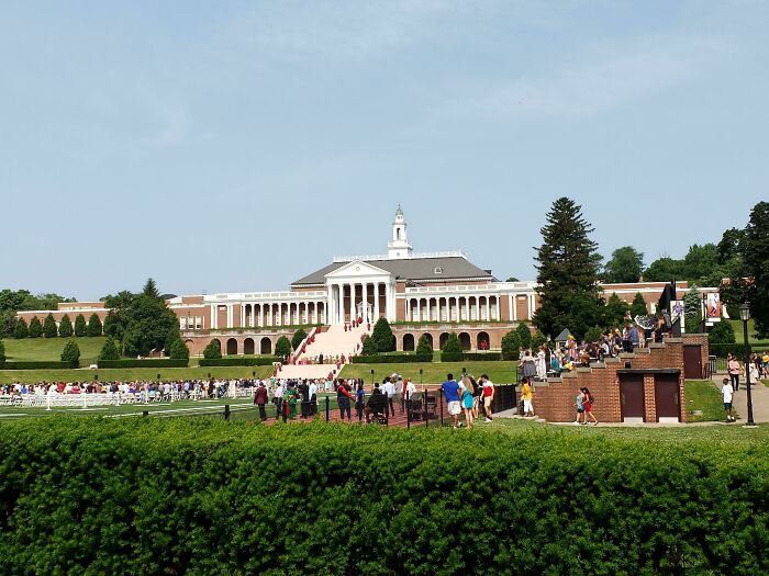 Historic American school building with people gathered outside during a sunny day.